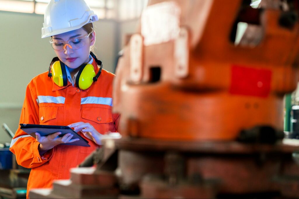 A female engineer expertly operates a industrial machine with a monitor, ensuring exacting standards.