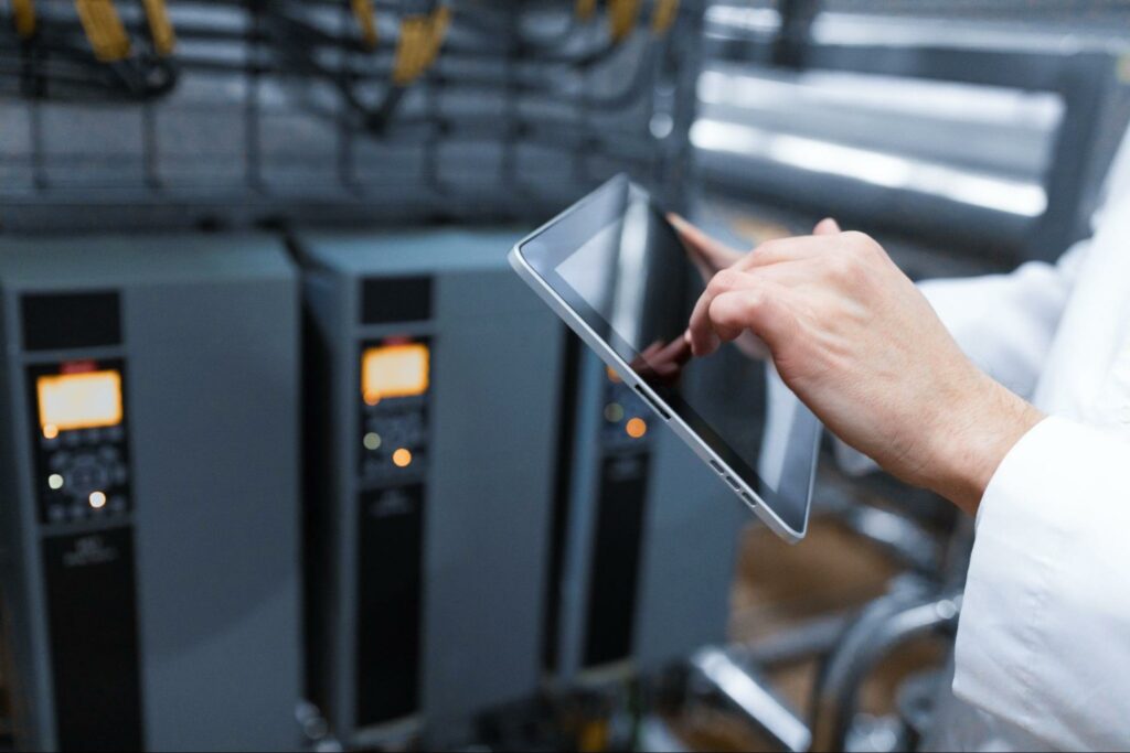 Technologist configuring a production line using a gray tablet, showcasing operational expertise, ensuring robust protection across industrial processes.